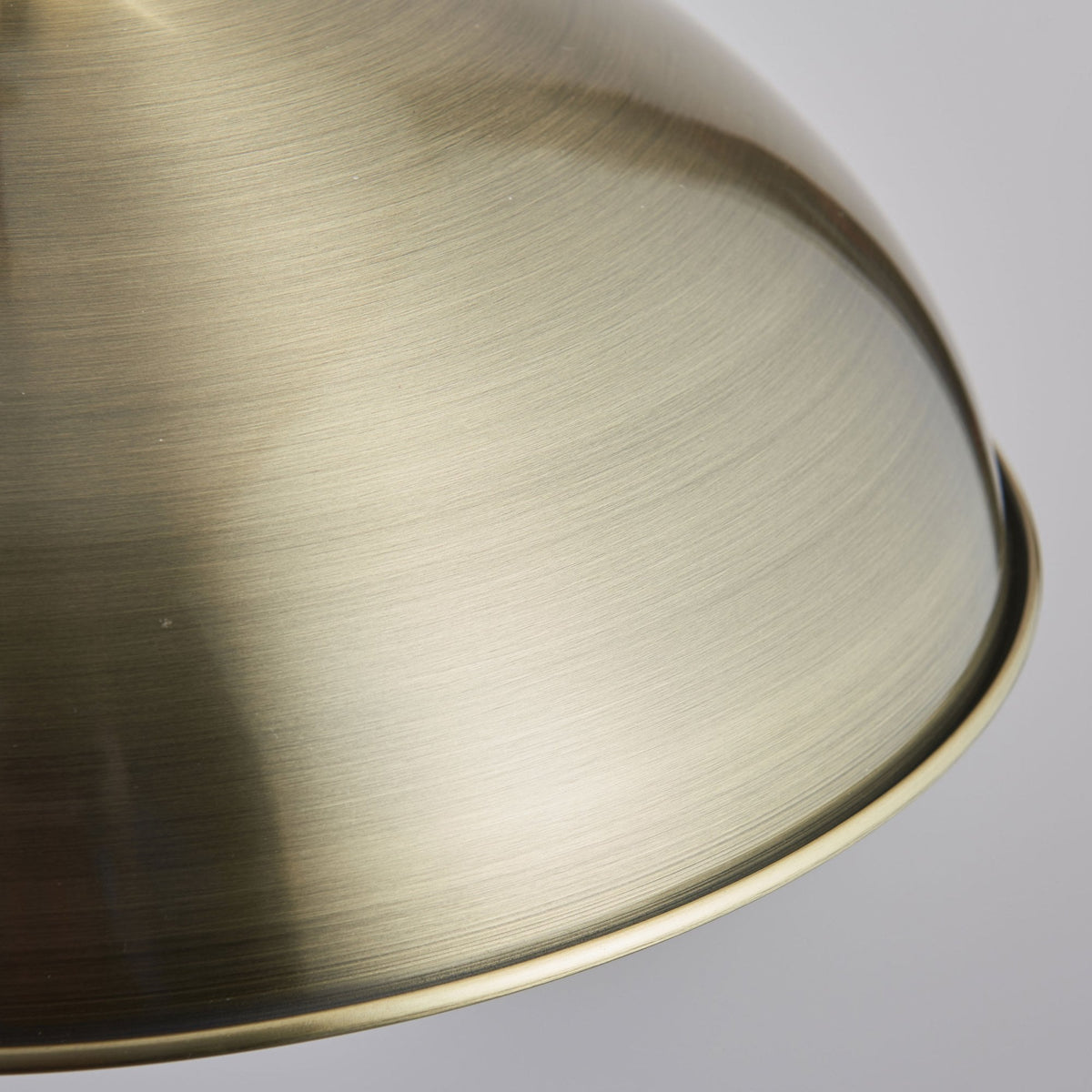 Close-up of the brushed brass texture on the dome shade of a pendant light.