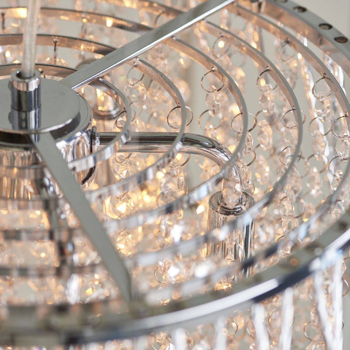 Close-up of the top of a silver chandelier, showing the clear crystal beads and the metal framework.