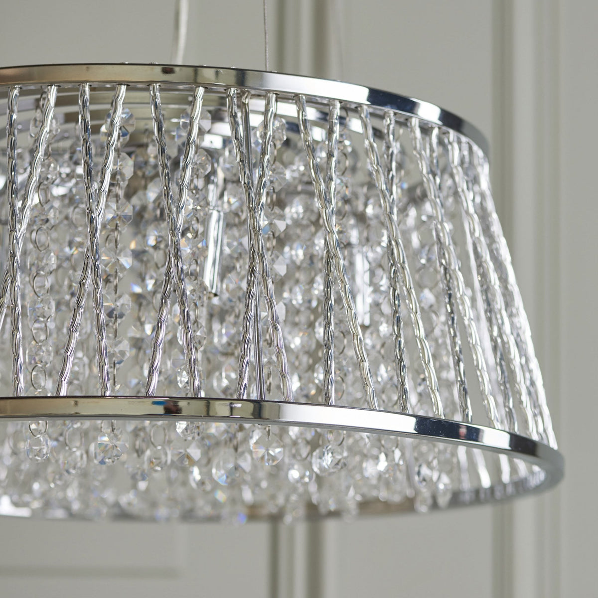 Close-up of a silver-framed chandelier with clear crystal beads, highlighting the texture and sparkle of the crystals.