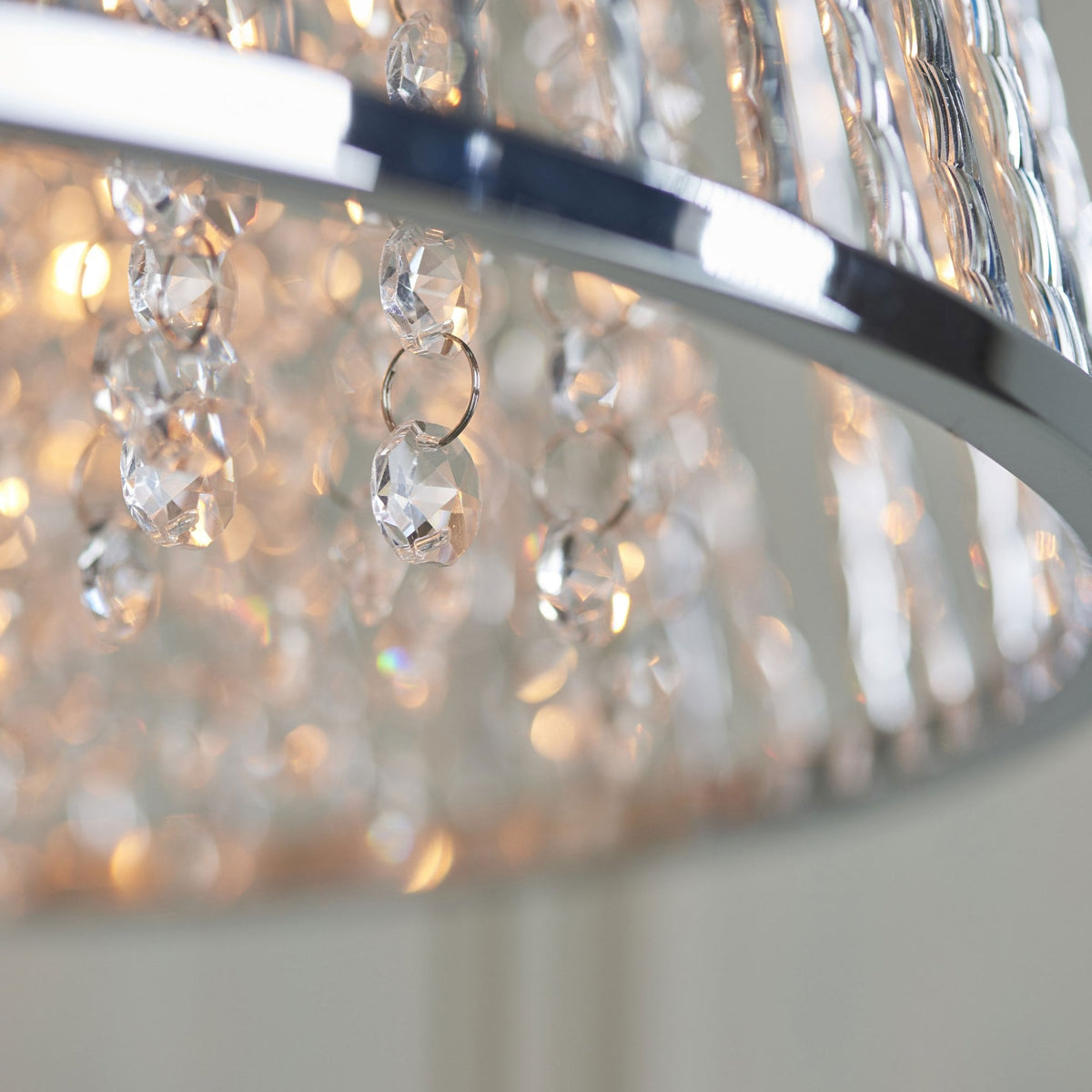 Close-up of the bottom of a silver chandelier, showing individual clear crystal beads dangling from the frame.