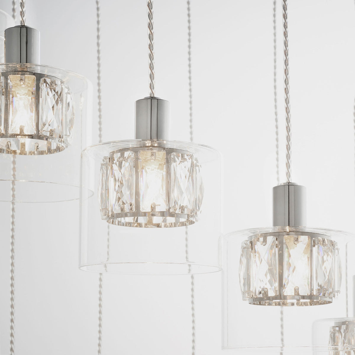 Three chandelier lights with clear glass shades and intricate crystal designs, hanging against a white background.