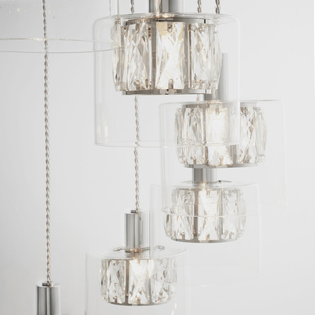 Close-up of three stacked chandelier lights, showing clear glass shades and detailed crystal elements.