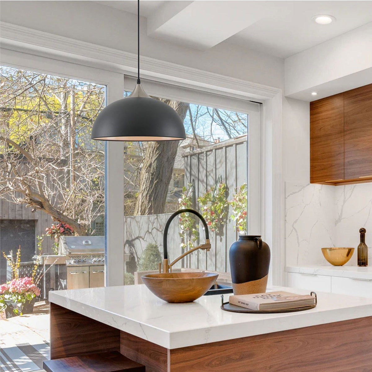 A black pendant light fixture hangs above a kitchen island with a sink.