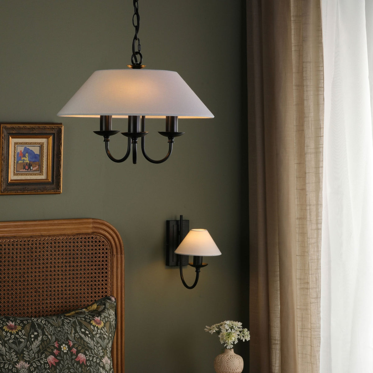 Bedroom with a chandelier, wall sconce, rattan headboard, and floral pillow.