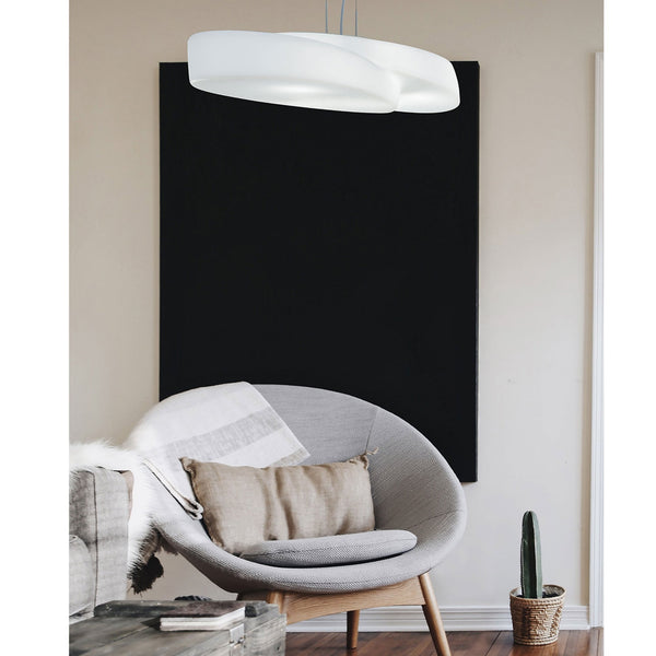 A stylish white curved ceiling light illuminating a living room with a grey armchair.