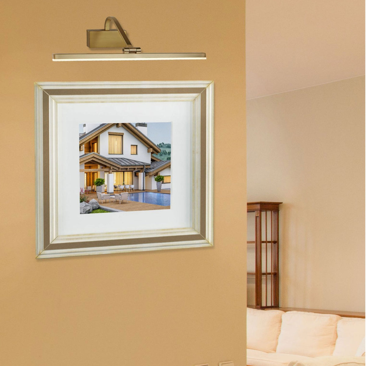 A picture light illuminating a framed photo of a modern house with a pool.