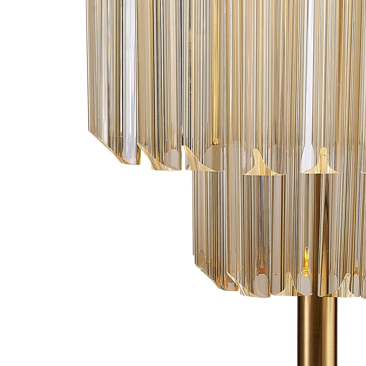 A close-up of the two tiers of clear glass rods that form the shade of the brass table lamp.