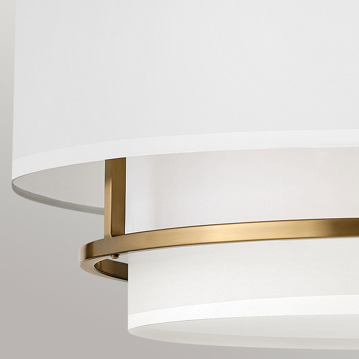 A close-up showing the layers of the white fabric shade and the brass frame details.