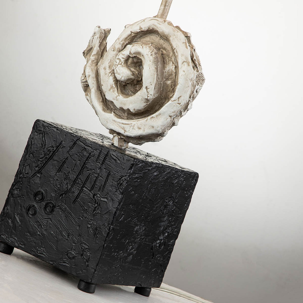 Detail of the lamp's textured dark cubic base and the white spiral decorative element.