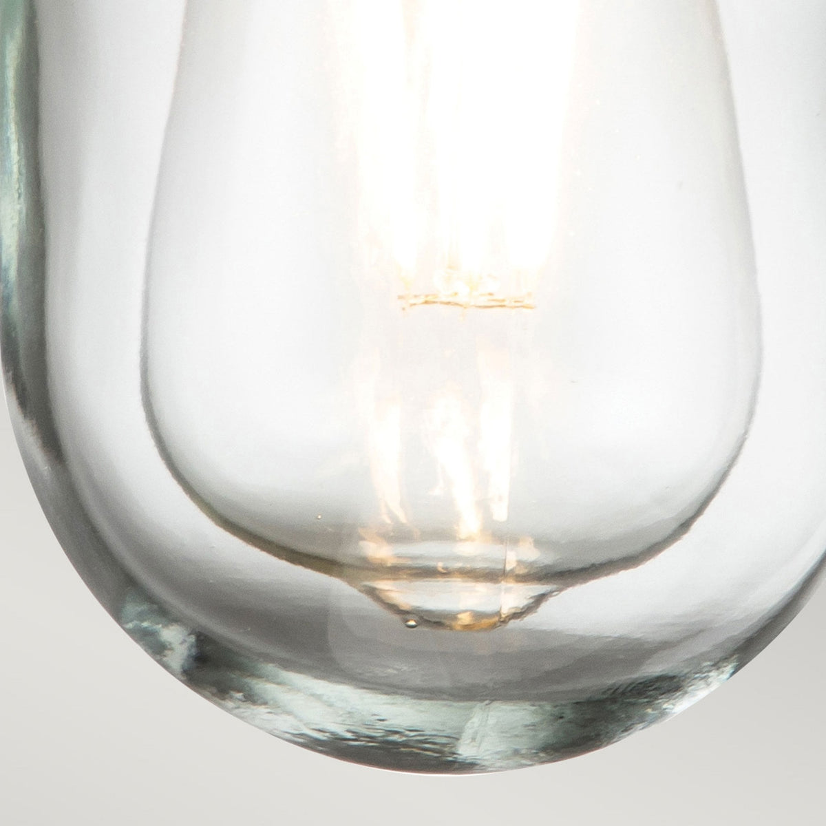 A close up of the clear glass shade and the E27 LED filament bulb's base.