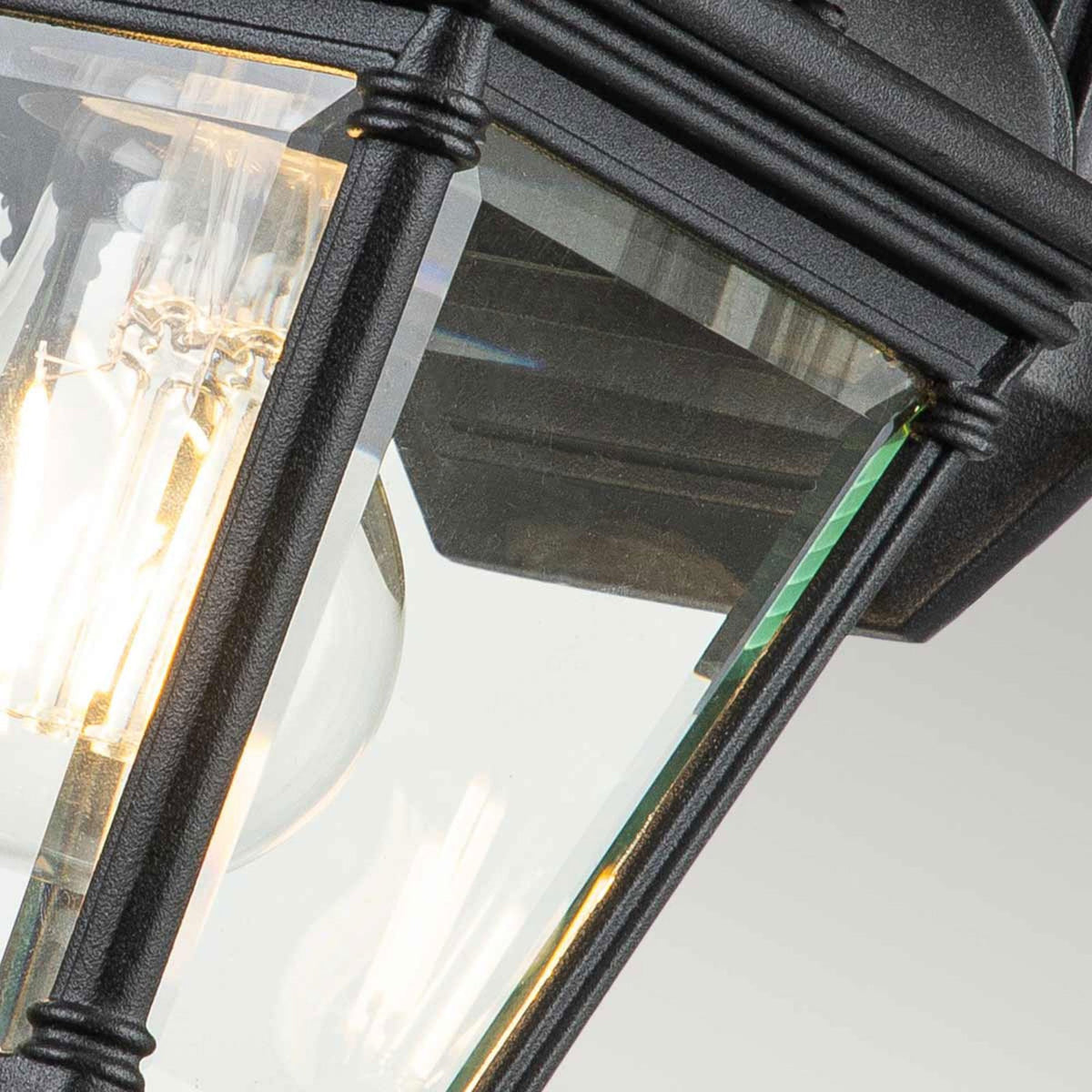Close-up of the black metal frame and clear glass panels of an outdoor wall light.