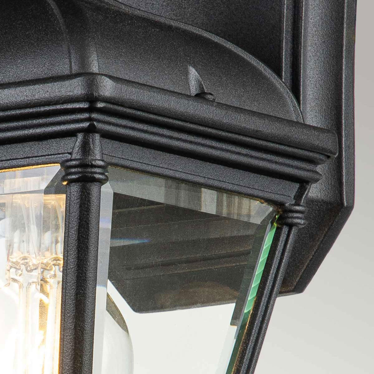 Detailed view of the black textured finish and clear glass of an outdoor wall light.
