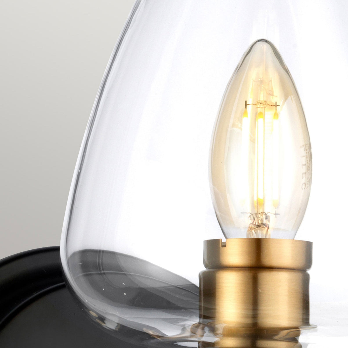 Close-up of the wall light showing the clear glass shade and Edison-style bulb.