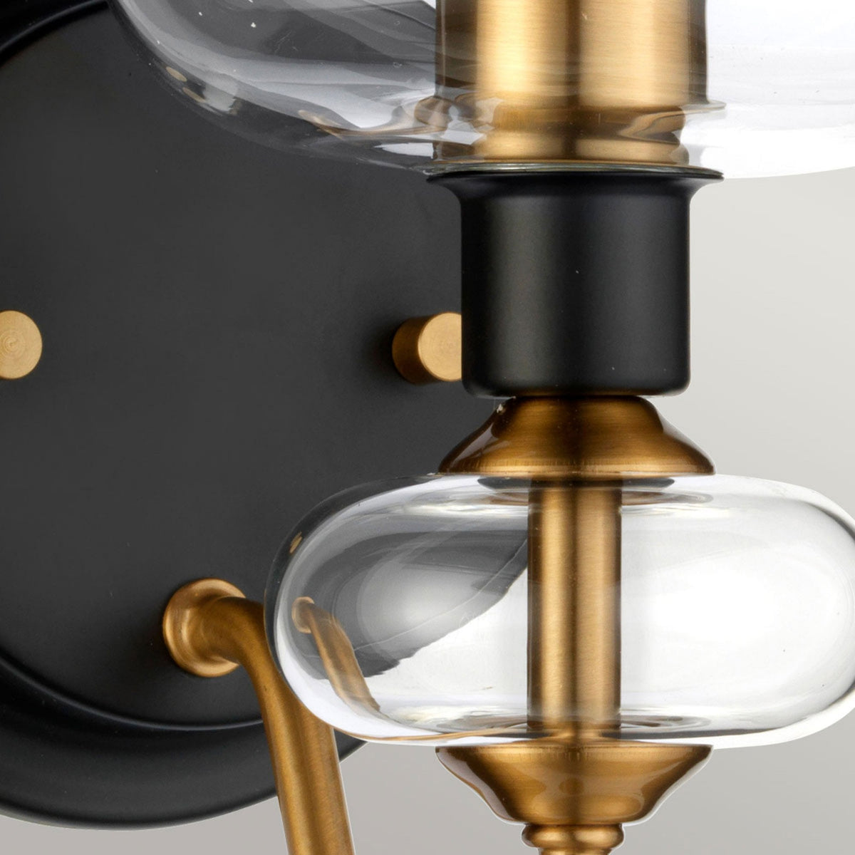 Detailed view of the wall light's black base and decorative gold-toned element.