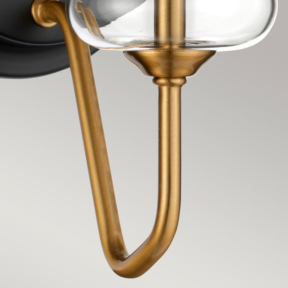 A close-up of the curved gold-toned metal arm extending from the wall light's base.