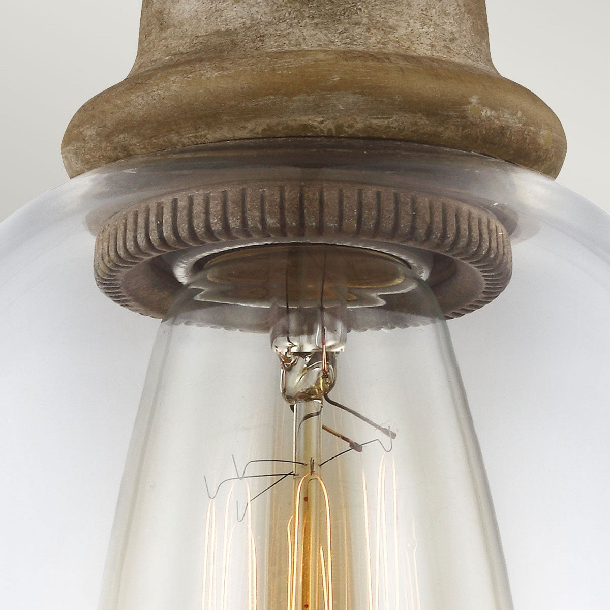 Detailed view of the bulb socket and filament within a clear glass pendant light shade.
