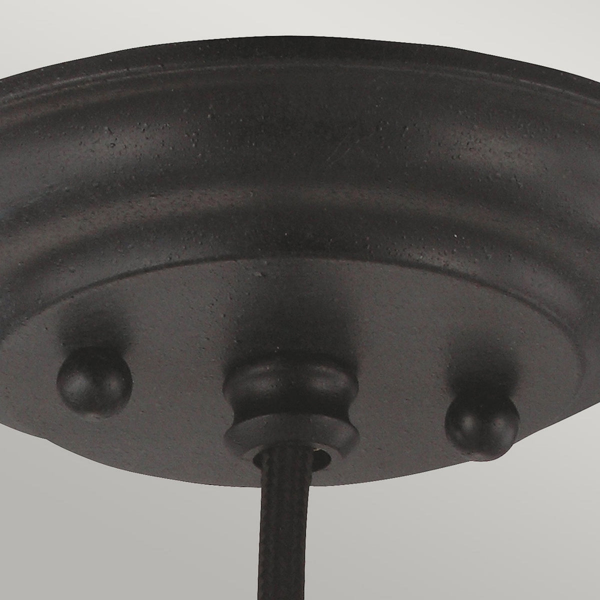 A close-up of the ceiling rose of a black pendant light fitting.