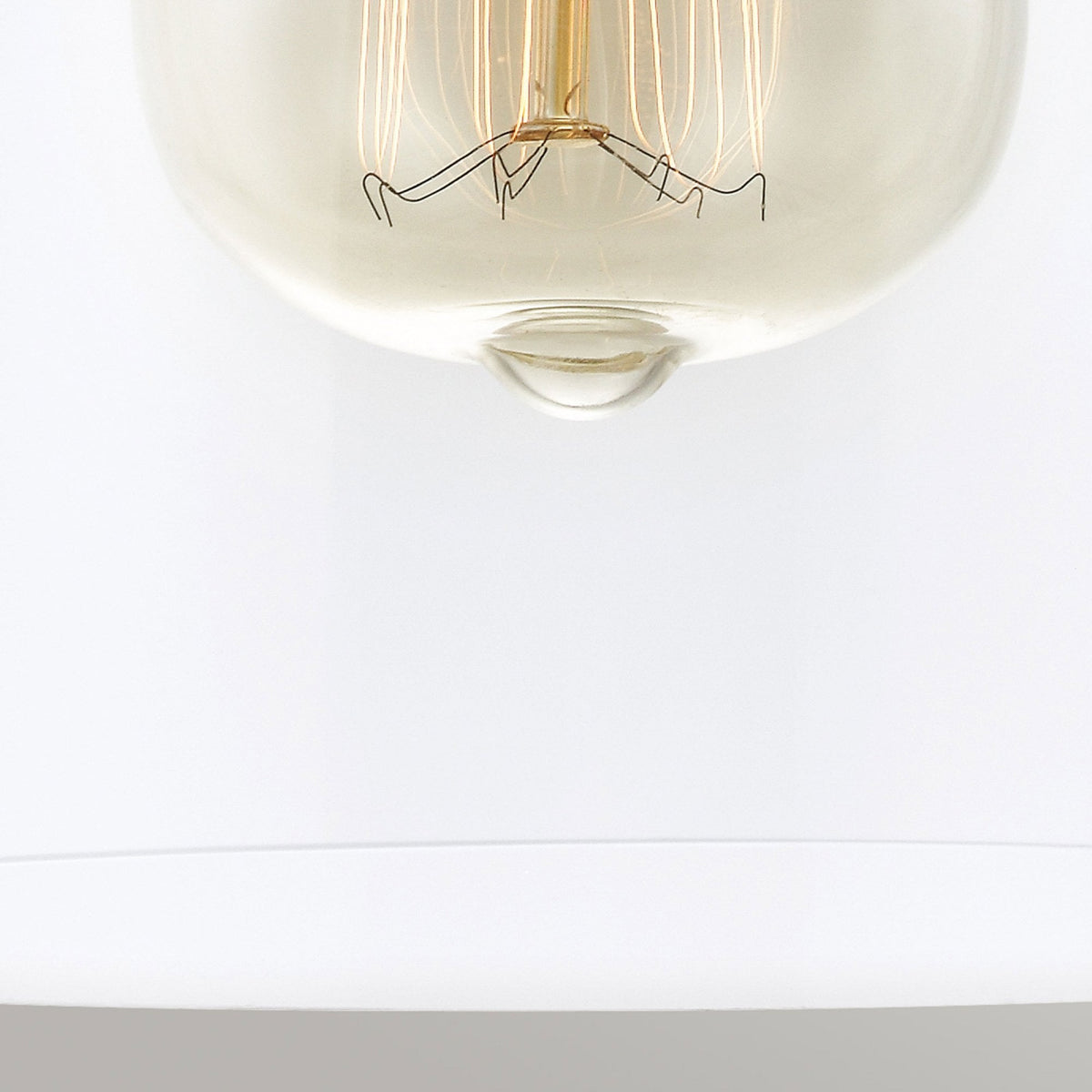 A close-up of the bottom of an exposed filament bulb in a clear glass shade.