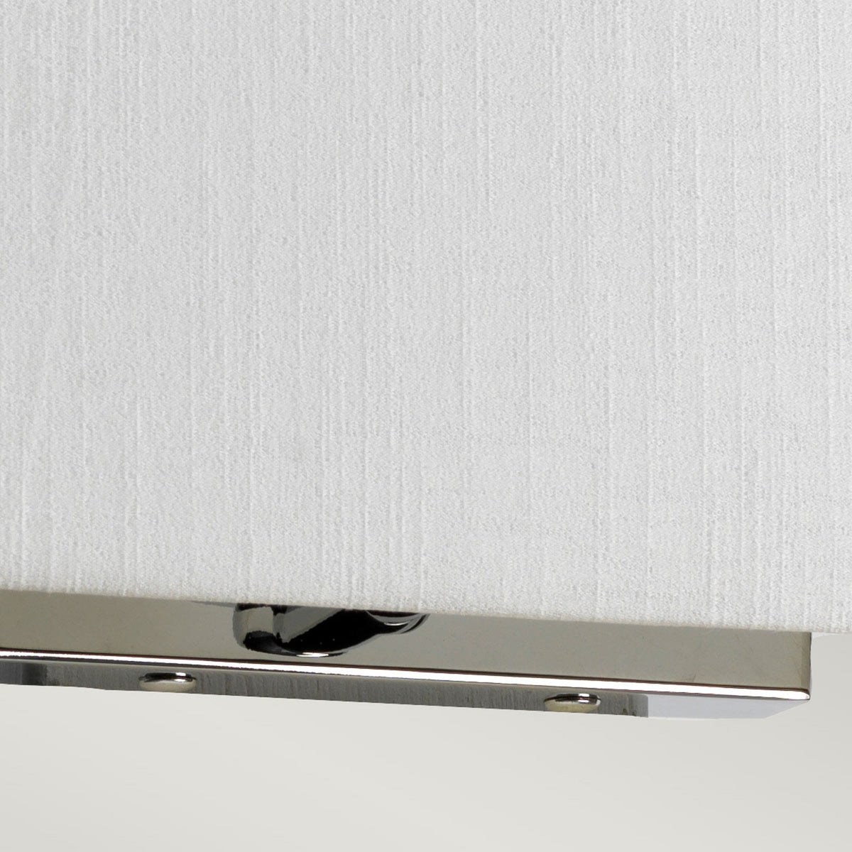 Detail of the polished chrome base supporting a white fabric wall light.