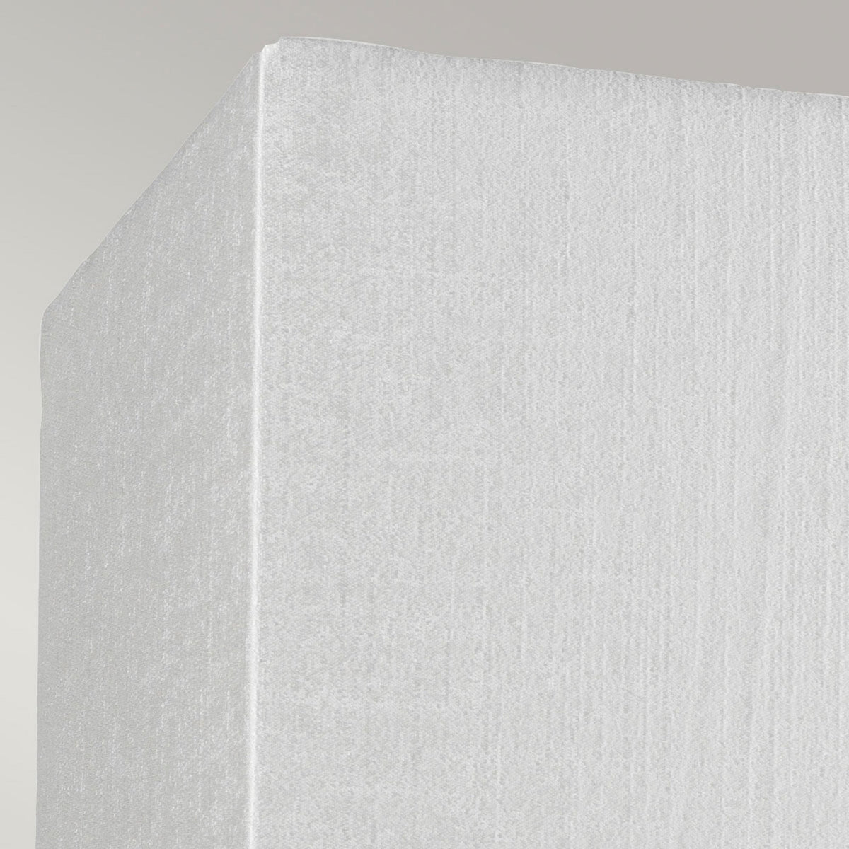 Corner detail of the textured white fabric shade of a modern wall light.