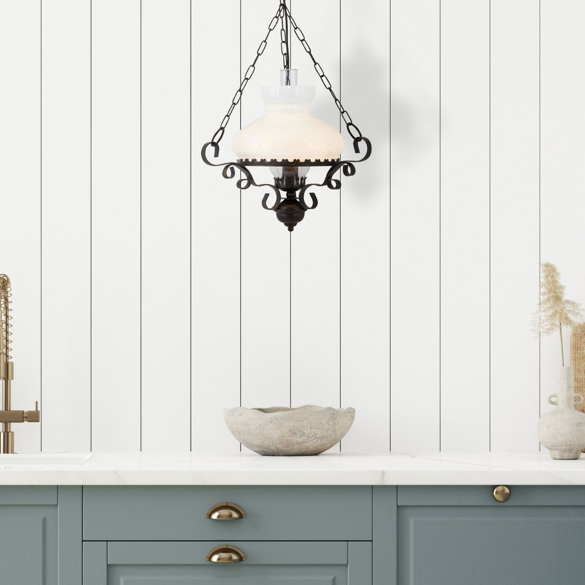 Rustic hanging light above a kitchen counter with blue cabinets and white panelled wall.