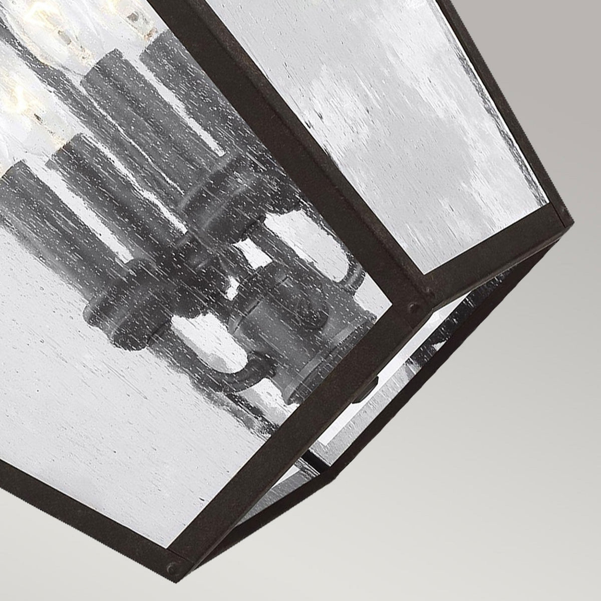 Close-up of the internal candelabra bulbs and seeded glass panels of the outdoor lantern.