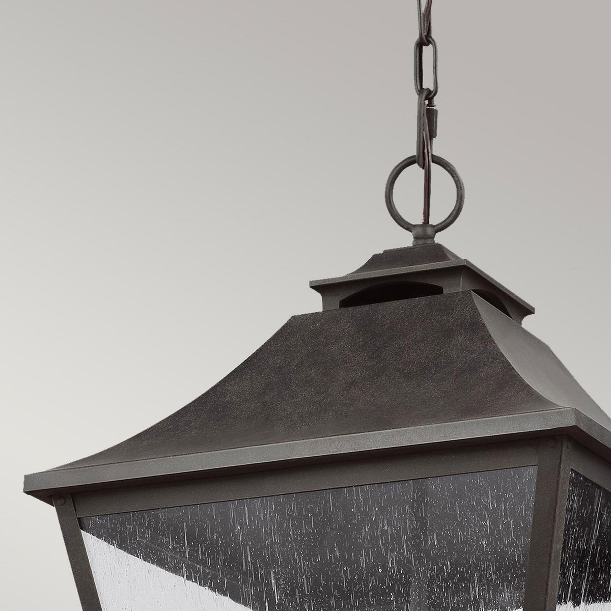 Detail of the chain and top of the dark-finished outdoor hanging lantern with seeded glass.