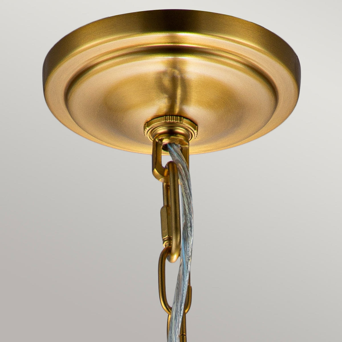 Close-up of the brass ceiling rose and chain attachment of the pendant light.