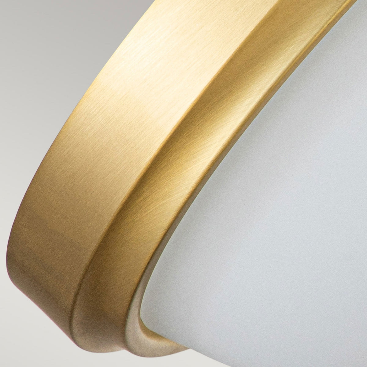 A detailed angle of the antique brass finish and white glass diffuser of the Capulet flush mount light.
