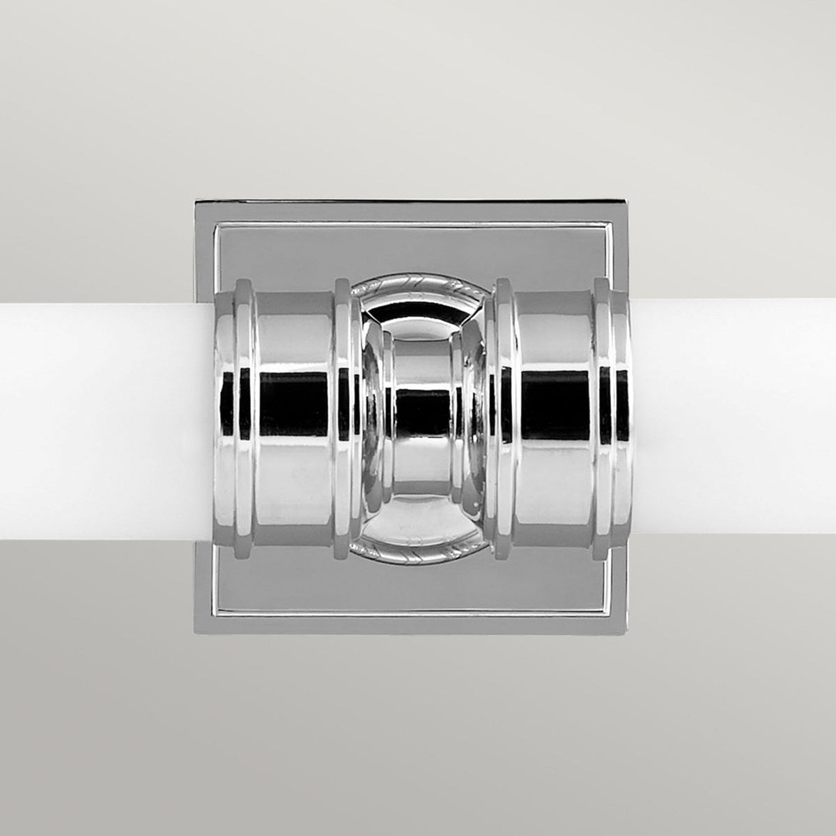 A close-up of the chrome-plated central fixture of a twin tube bathroom wall light.