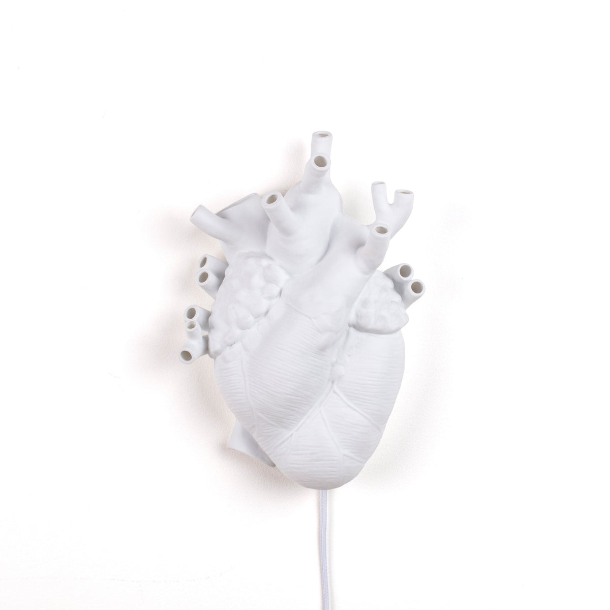 White anatomical heart lamp with visible wires against a plain white background.