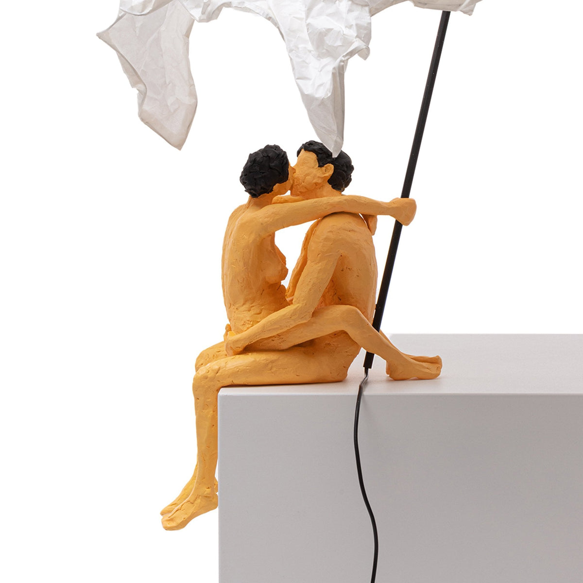 Close-up of a modern art lamp featuring a couple kissing under a white crumpled shade.