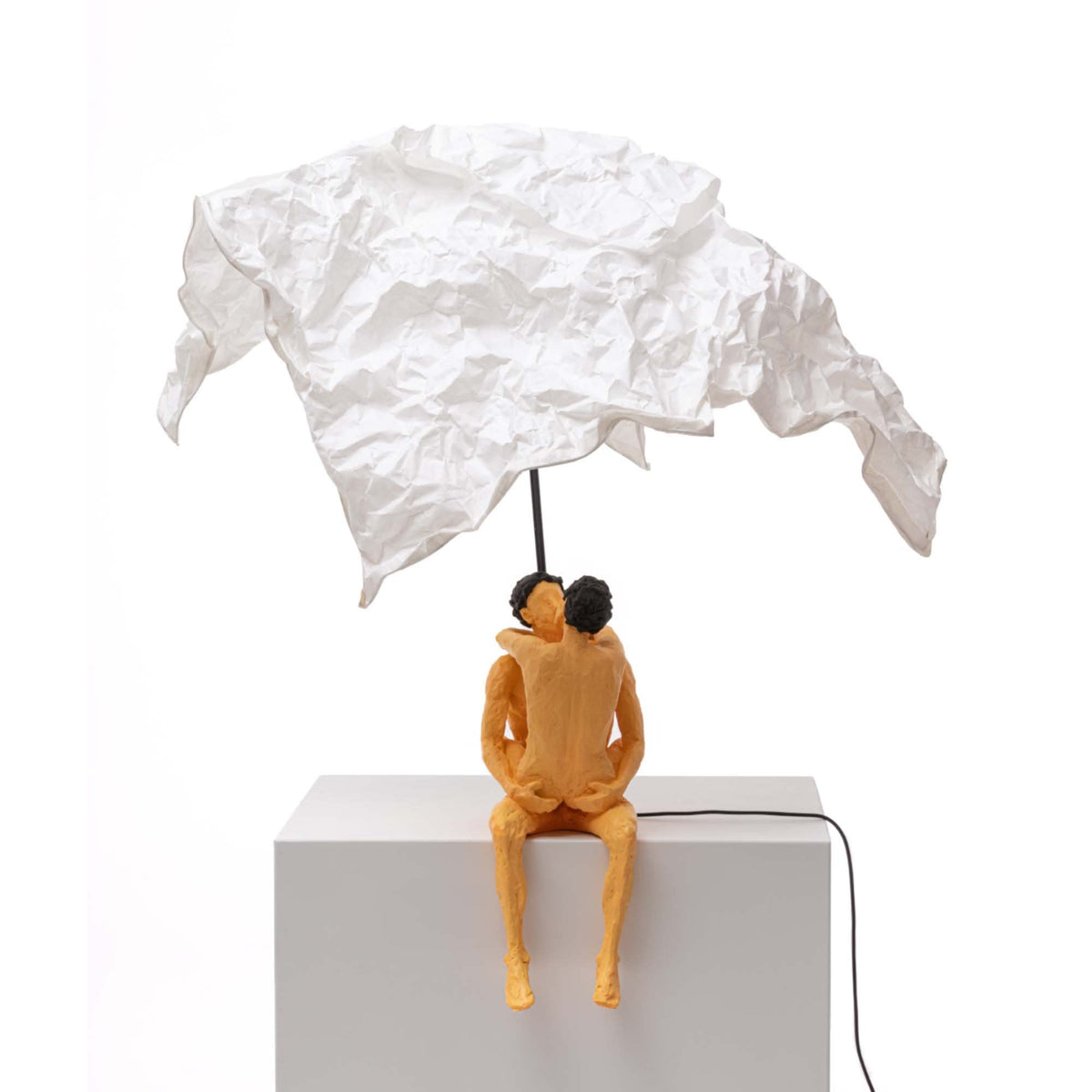 A modern art lamp with a couple embracing under a white crumpled shade, casting a warm glow.