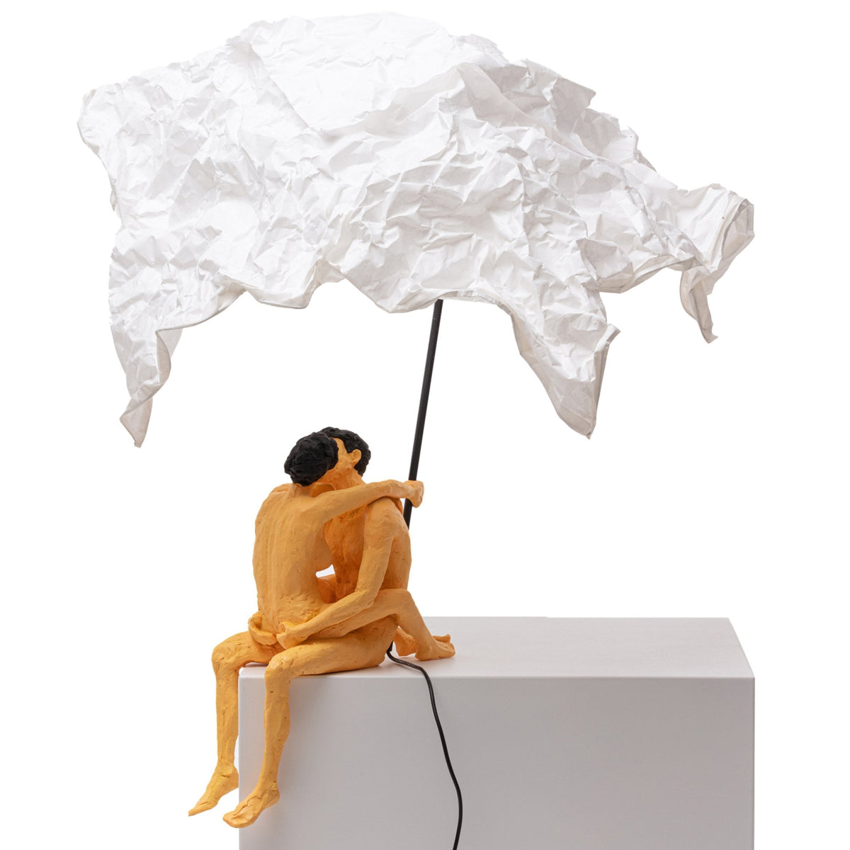 A modern art lamp with a couple kissing under a white crumpled shade, casting a warm glow.