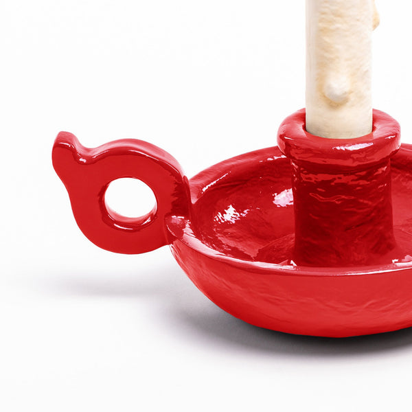 Close-up of the glossy red ceramic candle holder, showing its handle and rim.