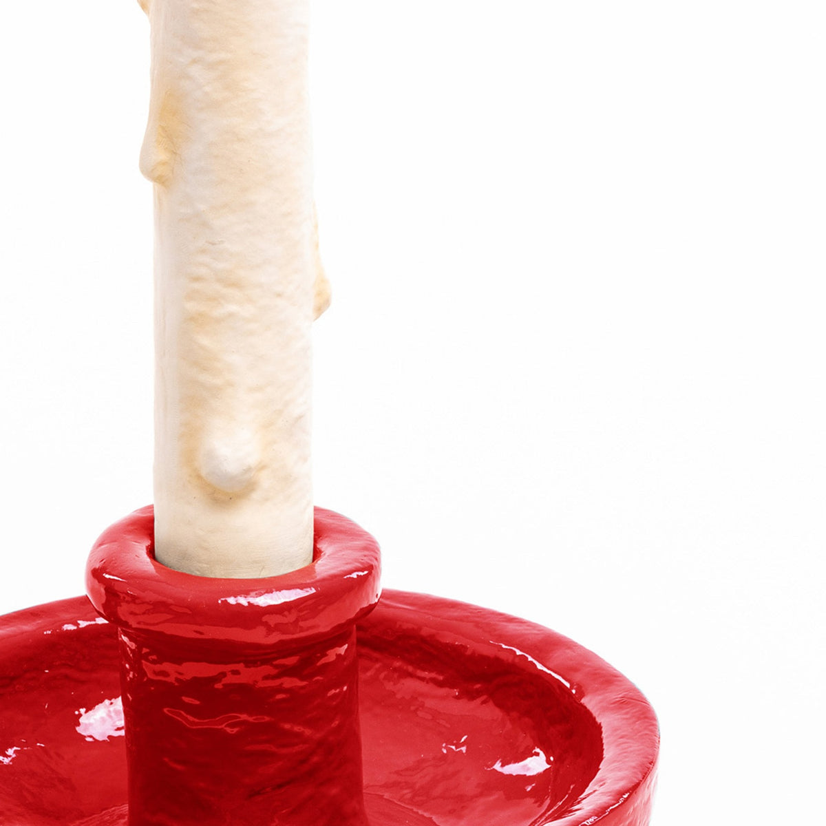 Close-up of the base of the faux candle seated in the glossy red ceramic holder.