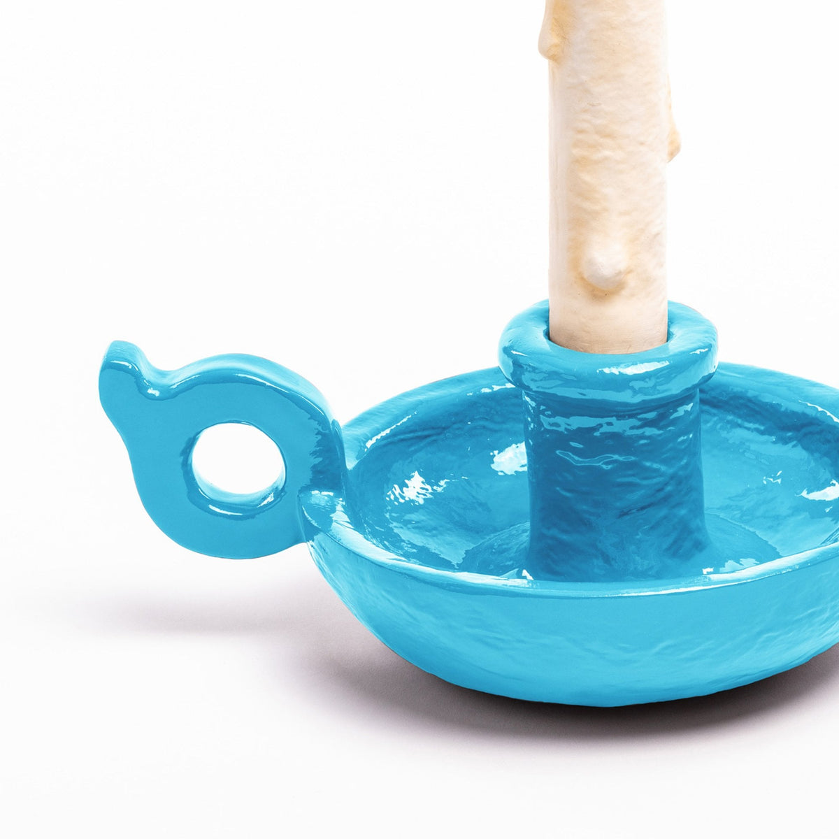 Close-up of the bright blue ceramic candle holder with a small handle, on white.