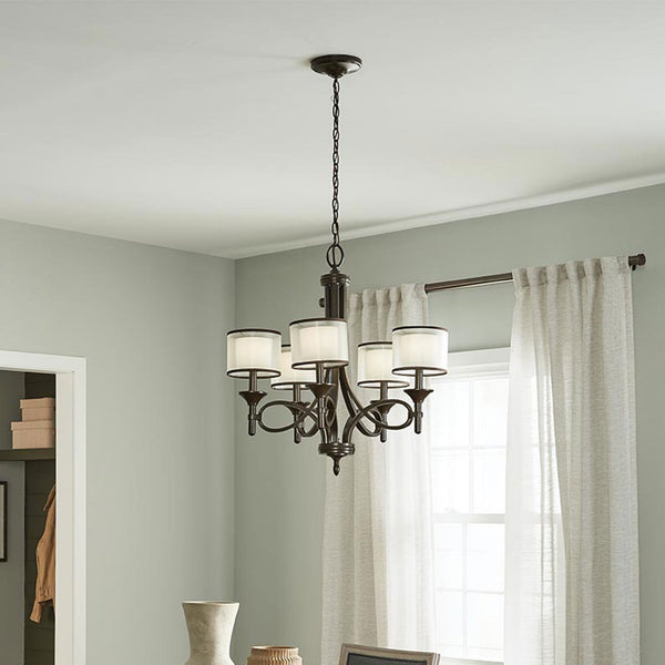 A dining room featuring a dark bronze chandelier with five drum shades.