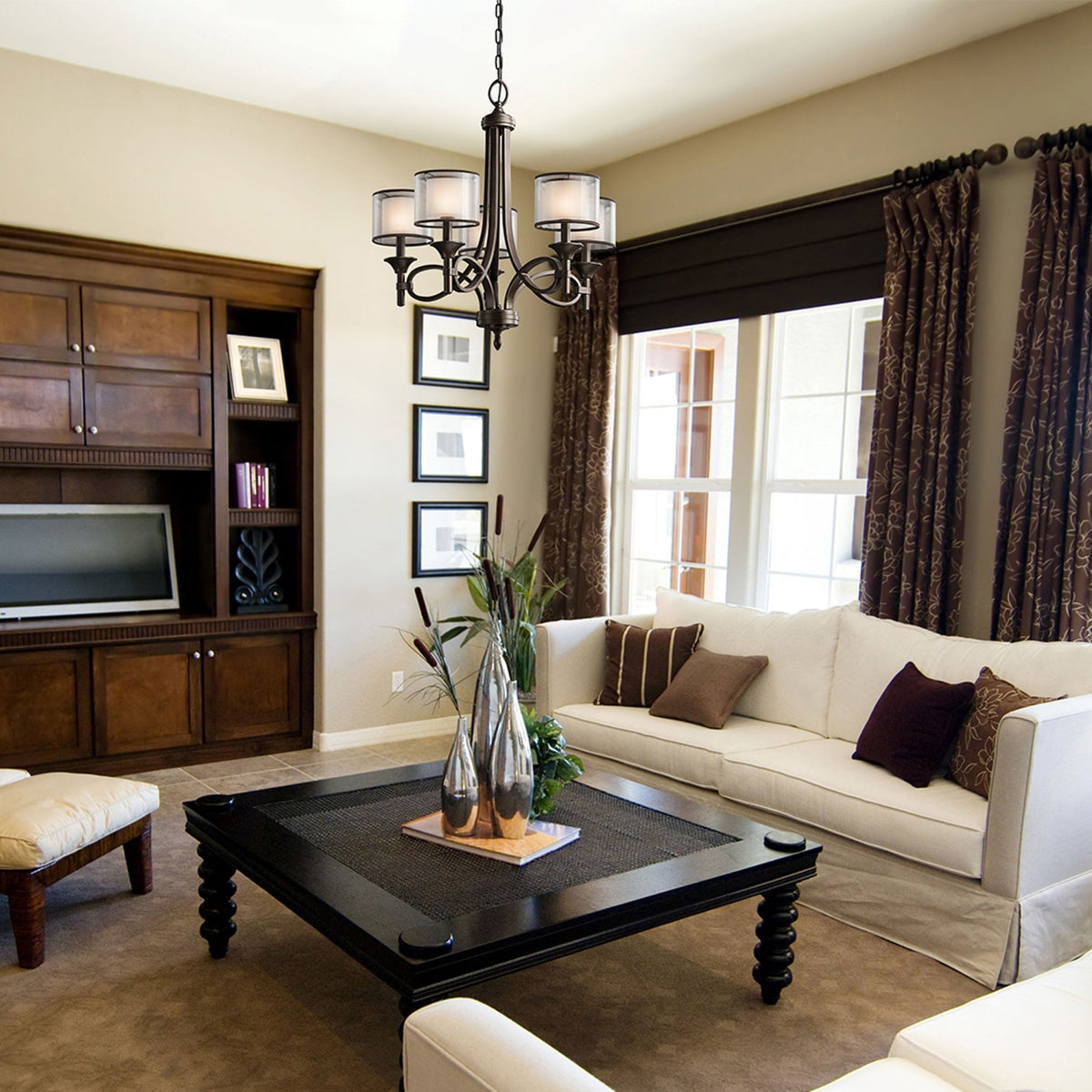 A living room with a dark bronze chandelier, white sofa, and dark wood furniture.