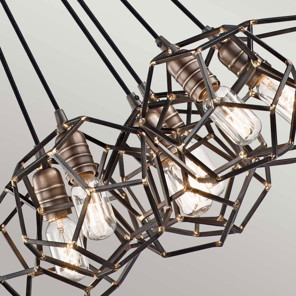 A close-up of the pendant's geometric metal cages, revealing the exposed Edison bulbs.