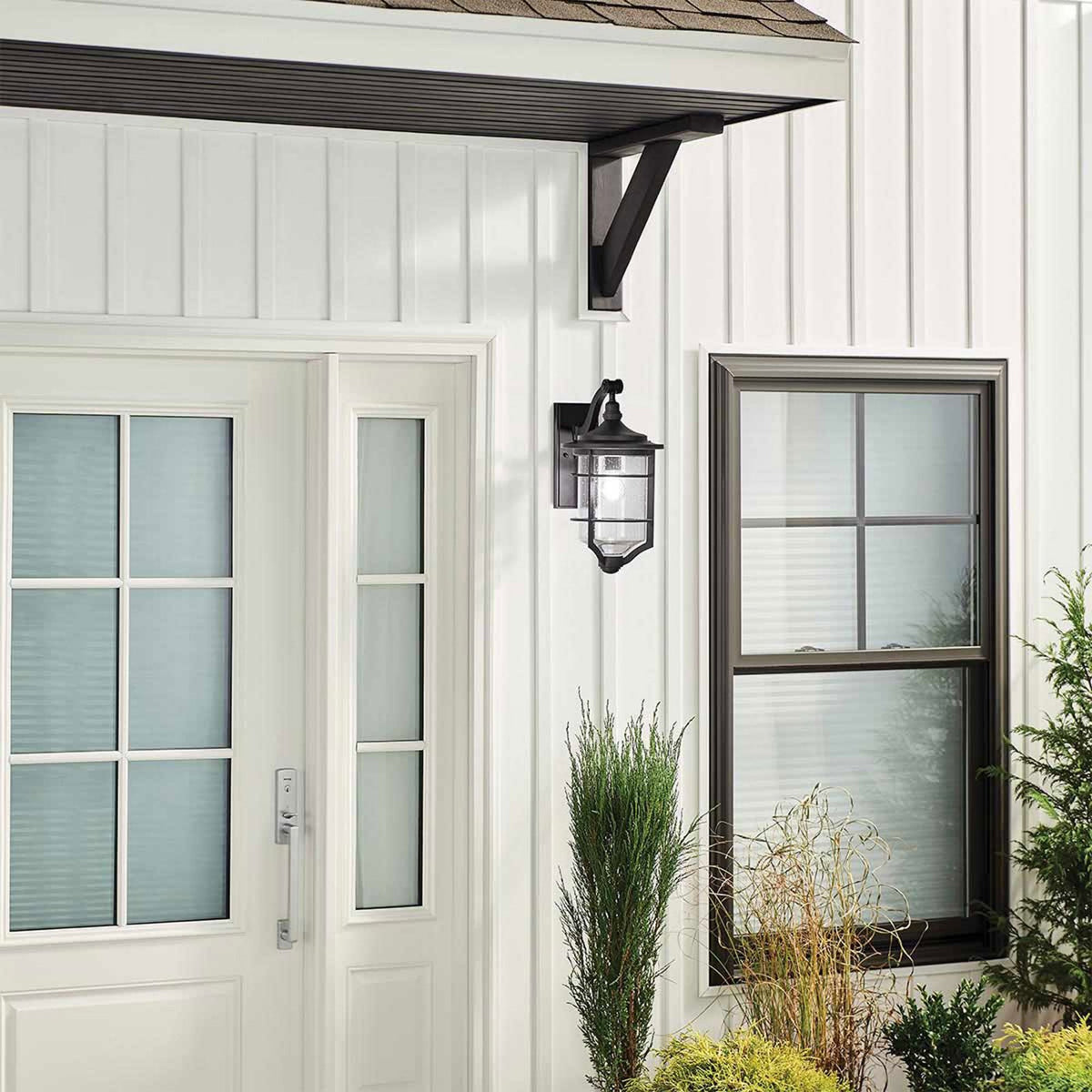 An outdoor wall light mounted on a white house, enhancing the home's exterior.