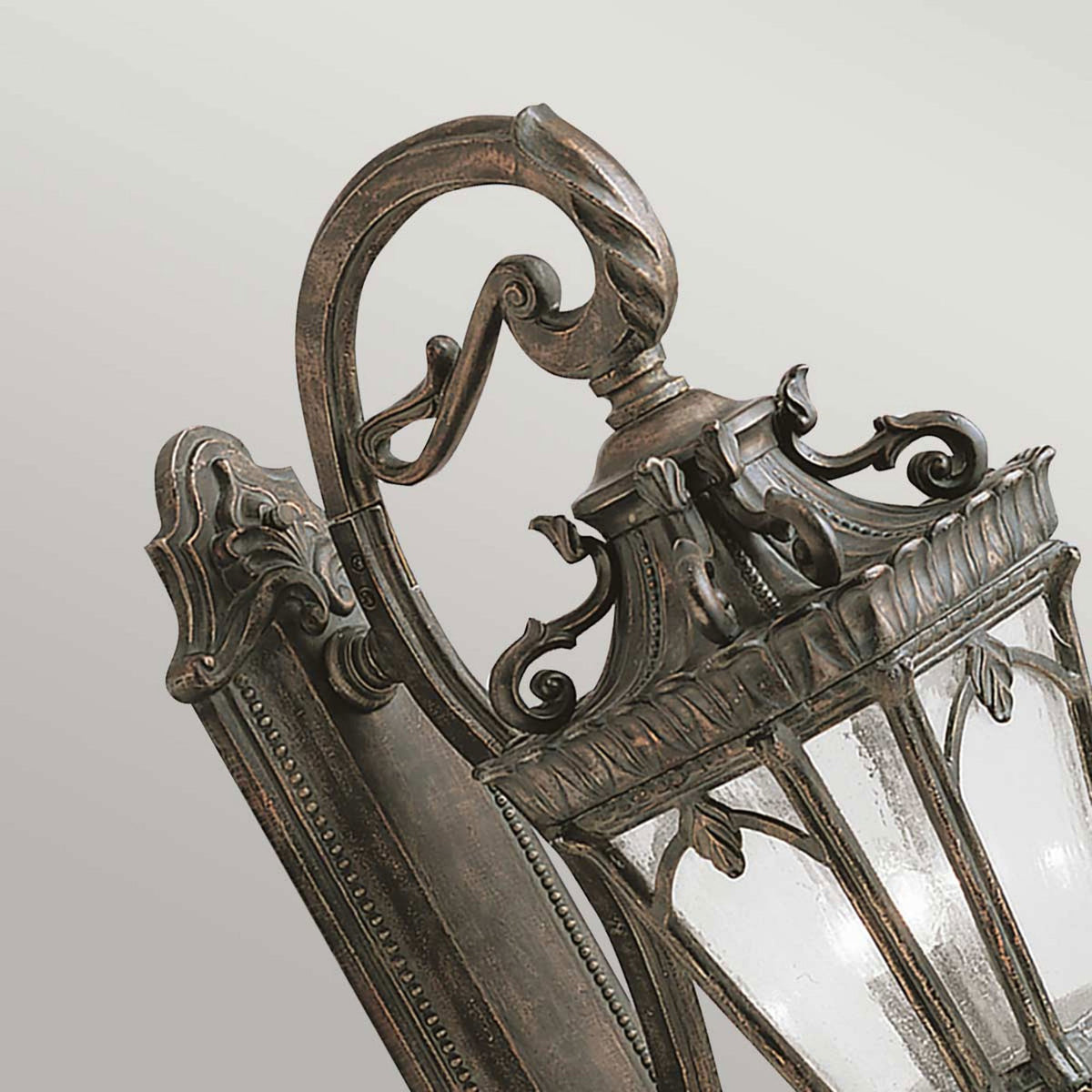 Close-up of the decorative top scrollwork and seeded glass of the wall light.