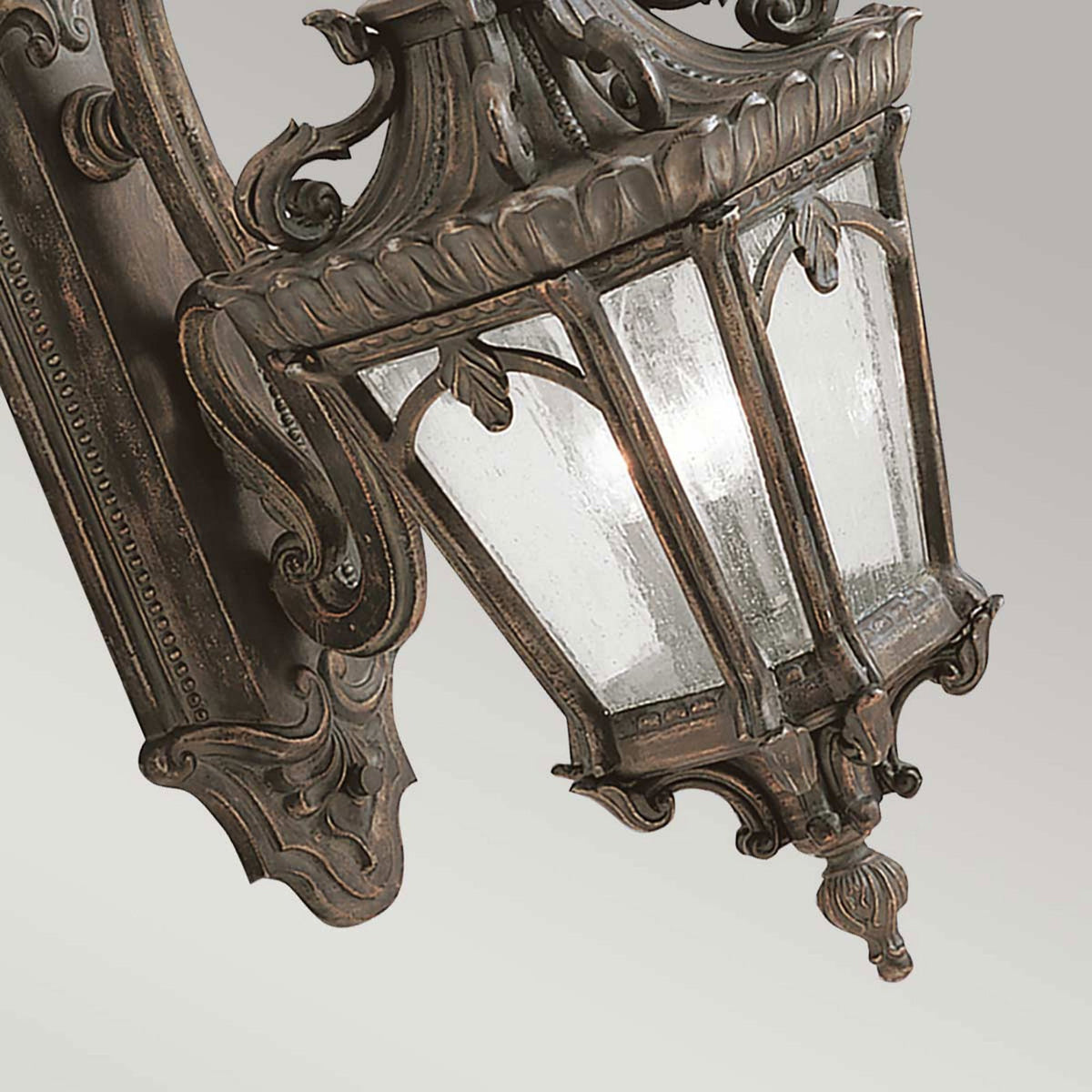 An angled view highlighting the seeded glass and intricate bronze detailing of an outdoor light.