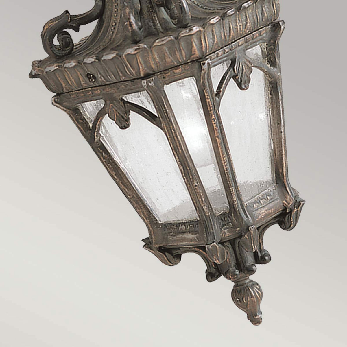 An angled view of an outdoor hanging lantern, showcasing its textured glass and bronze finish.