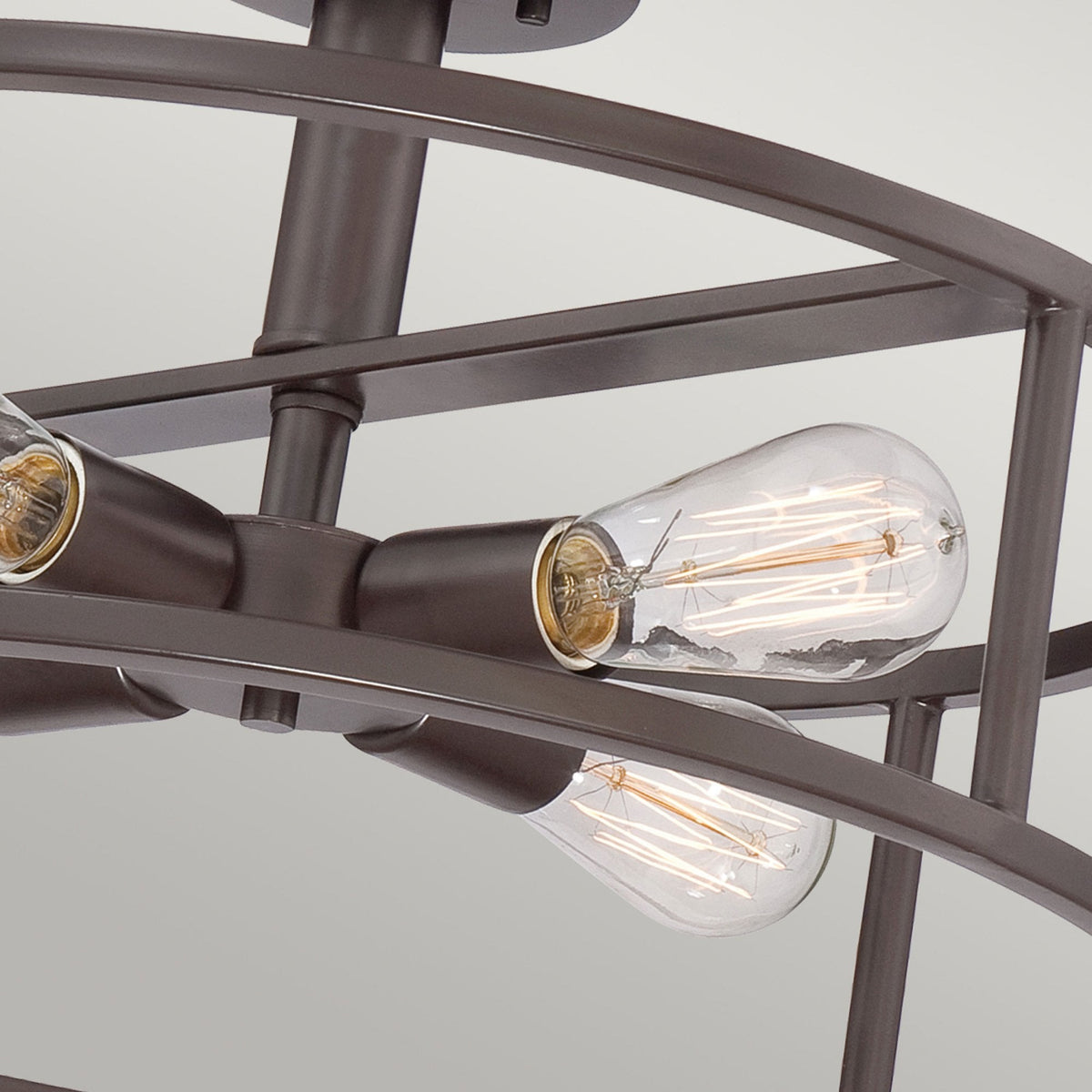Detailed view of the industrial-style exposed bulbs in a bronze semi-flush light fixture.
