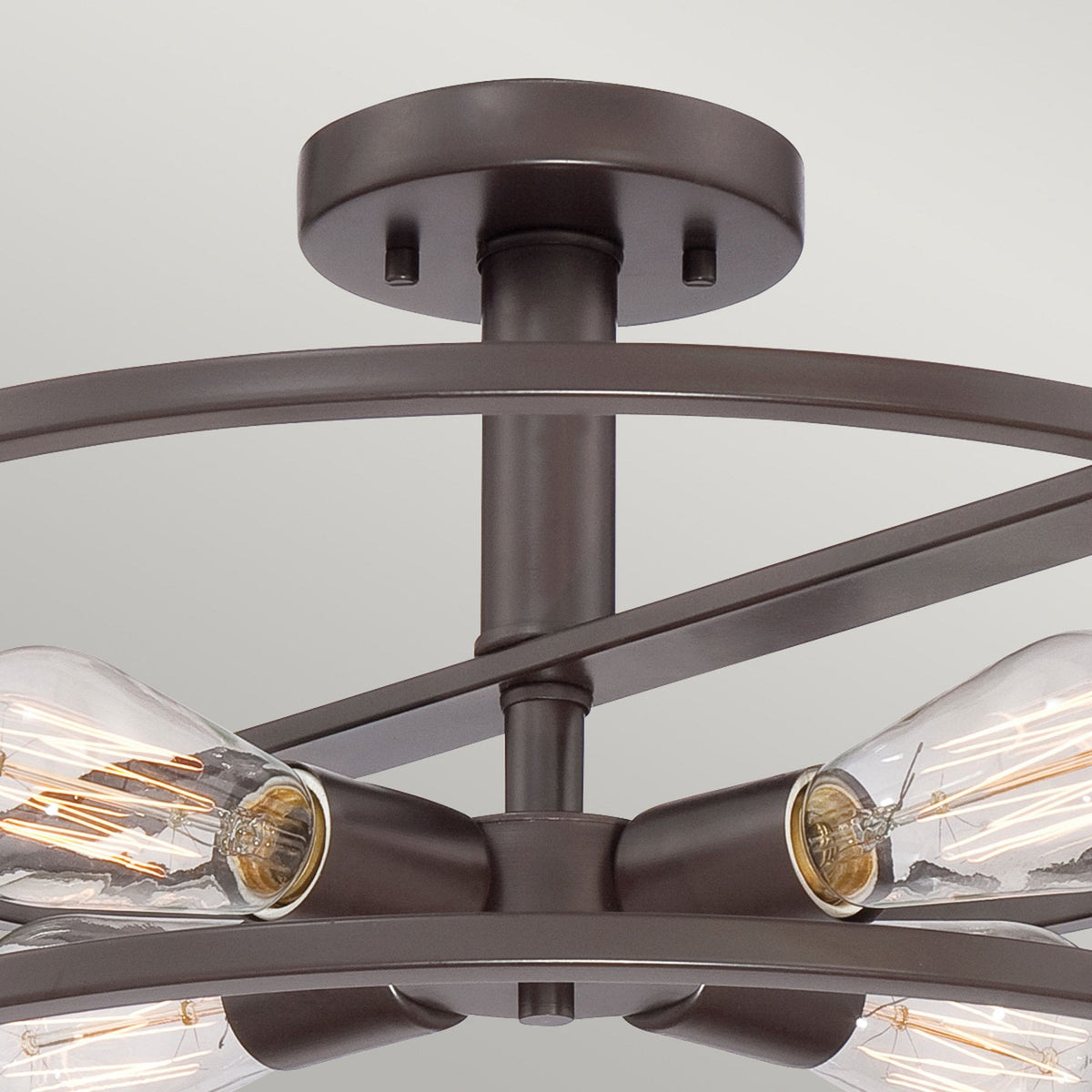 Top-down close-up of the bronze frame and exposed bulbs of a semi-flush ceiling light.