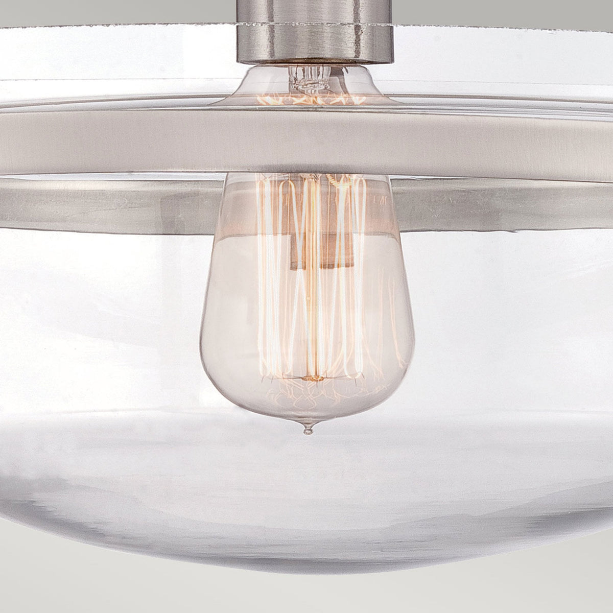 A close-up of the exposed Edison-style bulb within the clear glass bowl of the light.