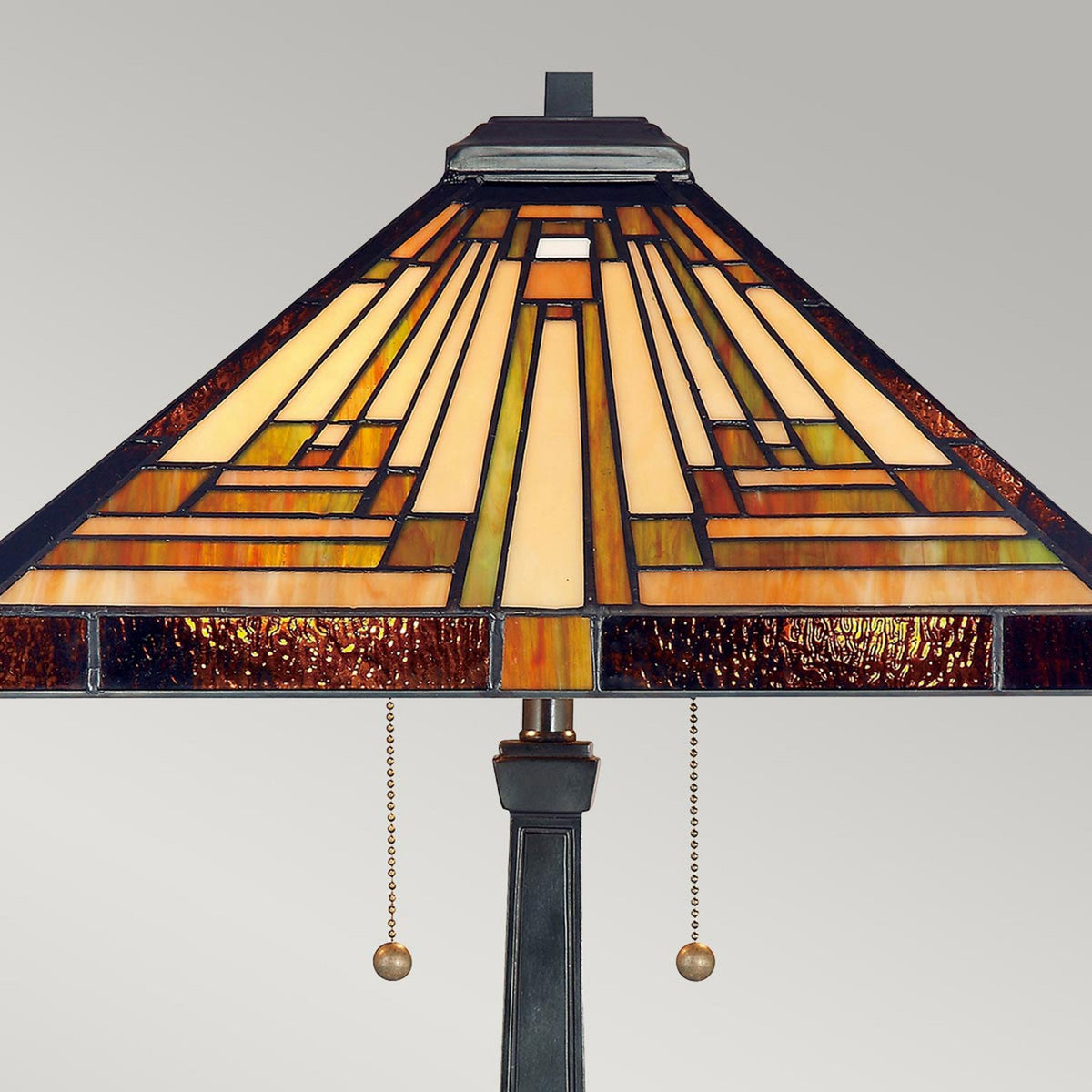 The stained-glass shade of a vintage table lamp, featuring geometric patterns in warm tones.