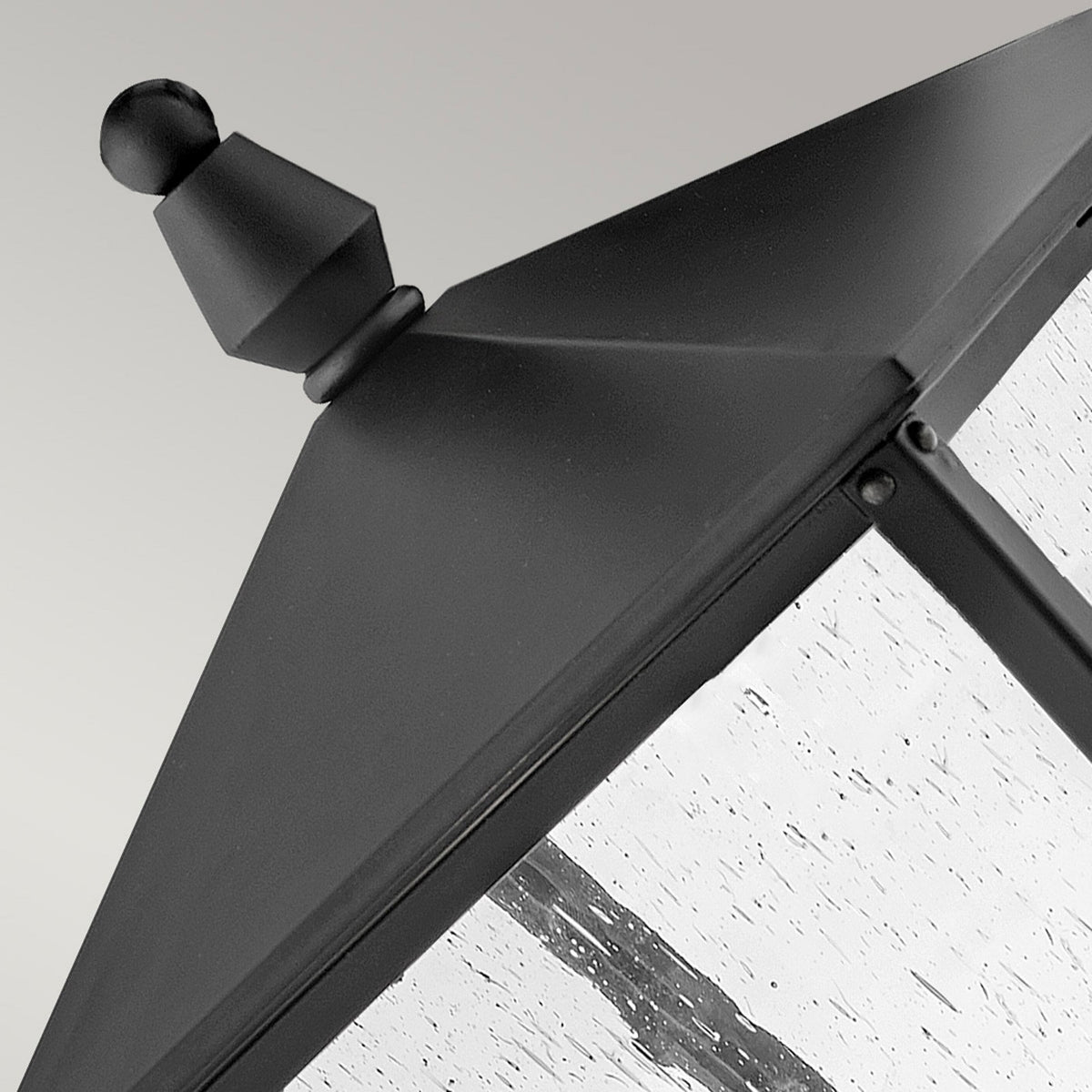 Close-up of the decorative finial and peaked roof of an outdoor post light.