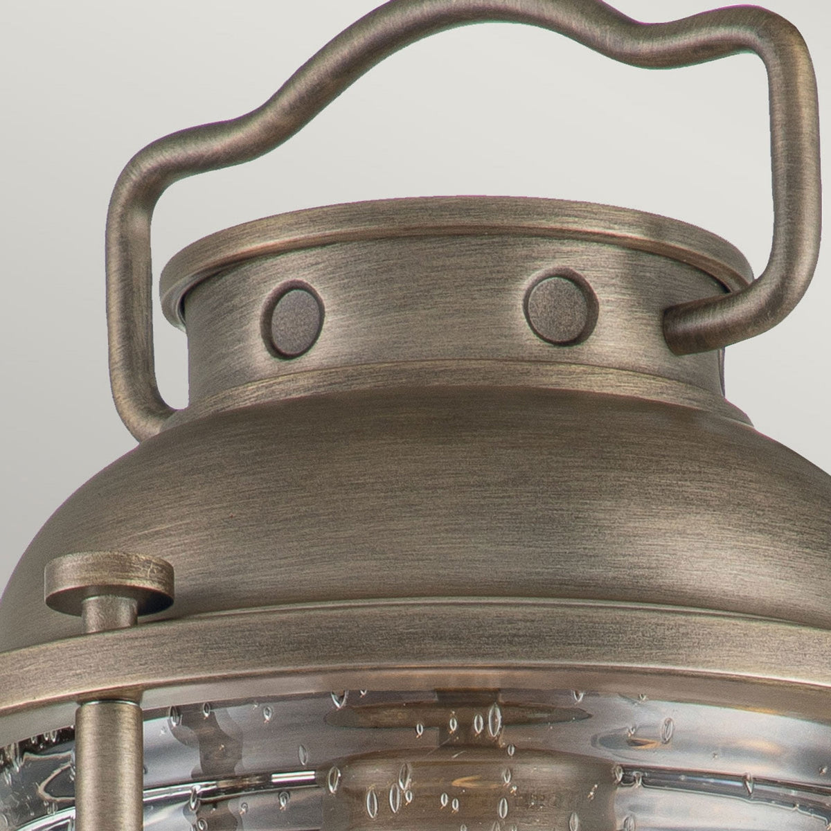 A close-up of the top of a bronze outdoor lantern, showing the handle and detailing.